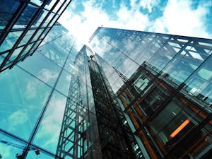 A striking view of a modern glass skyscraper reflecting the sky and clouds.
