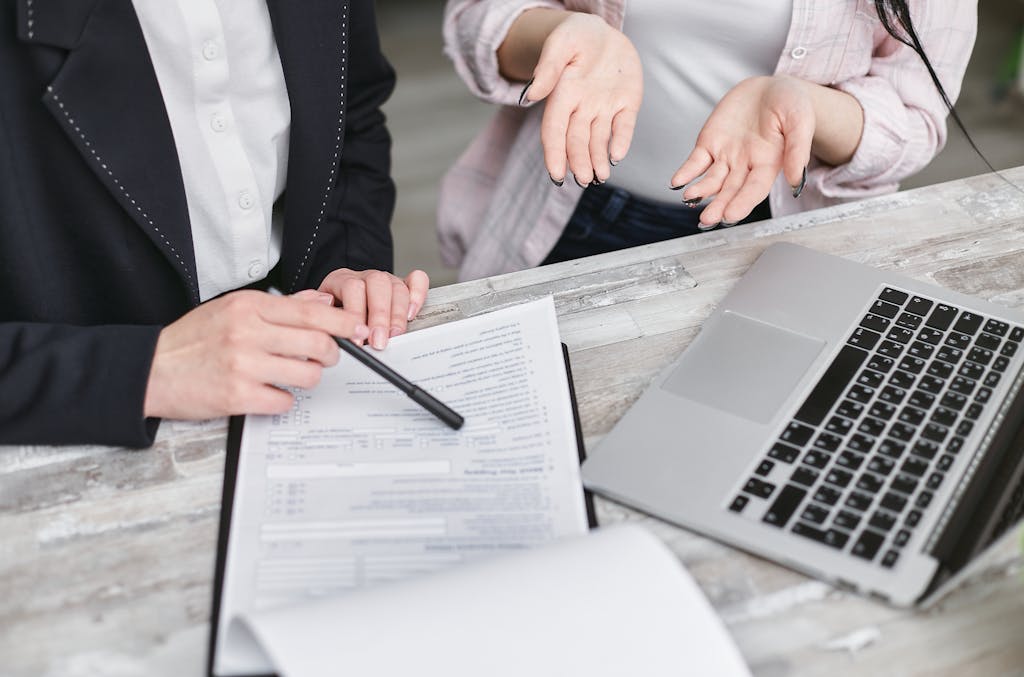 Foto von Mikhail Nilov Two professionals discussing a contract at a business meeting with documents and a laptop.